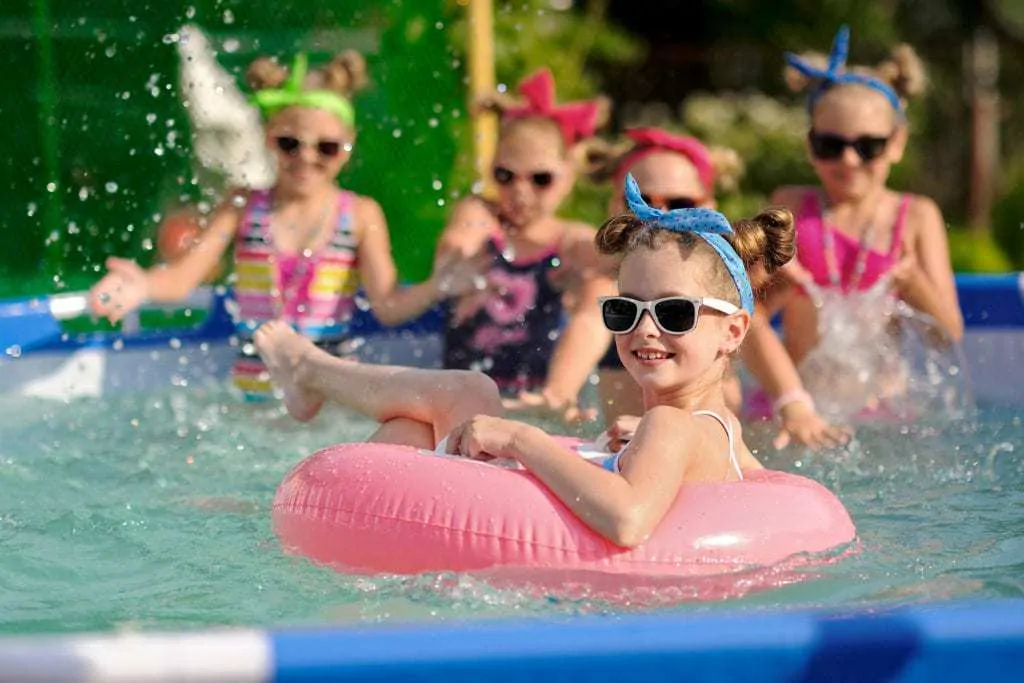 Group of young girls wearing sunglasses floating in inner tubes having some pool fun.